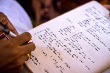 Kayıt için elinde kalem tutan bir kadınla imza, belge ve evlilik. Gelin, kültürel törende yasal evrakları veya misafir defterini imzalıyor.