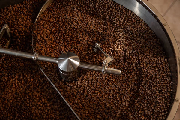 Roasting coffee. Coffee beans in a roasting machine. Cropped shot, close-up, horizontal, background. Concept of production and industry