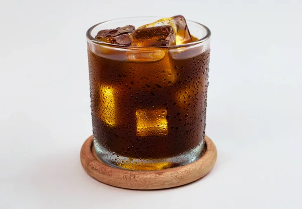 Bir bardak buzlu americano kahvesi. Bardak ıslak ve yoğunlaşmış görünüyor. Beyaz arka planda izole edilmiş.