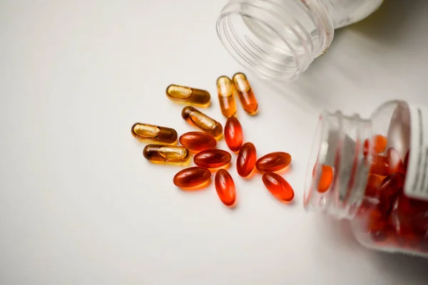 Bazı haplar beyaz bir masanın üzerine konteynerlerinden dökülüyor. Sağlık ve Tıp Konsepti