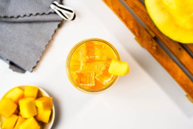 Taze, nefis bir mango suyunun düz yatağı. Şeffaf cam bardakta buzlu içecek kavramı.