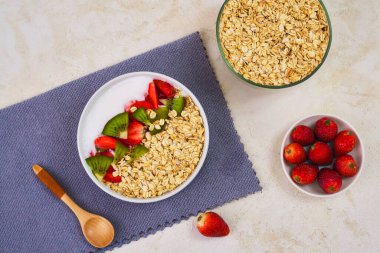 Lezzetli ve sağlıklı bir gecelik yulaf tabağı üzerinde canlı dilimlenmiş kivi ve taze çilek, besleyici bir sabah yemeği için hazır..