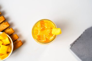 Taze, nefis bir mango suyunun düz yatağı. Şeffaf bardakta buzlu içecek. Vitamin zengini içecek konseptleri.