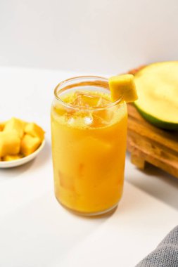 Buzlu mango suyu ve beyaz arka planda birkaç dilim mango meyvesi..