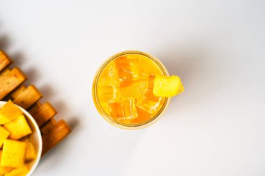 Beyaz bir arka planda taze mango meyvesi dilimlenmiş bardaktaki düz mango içeceği..