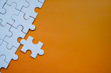 Tek bir beyaz yapboz parçası turuncu arkaplandaki bağlantıyı tamamlamak üzere. Boşluğu kopyala