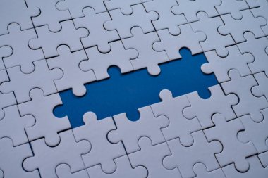 Beyaz yapboz parçaları, önemli bir parçanın eksik olduğu merkezi mavi bir boşluğu sarar. Boşluğu Kopyala