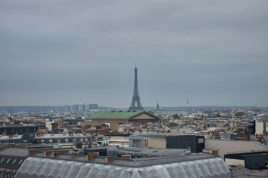 Lafayette Galerileri 'nin çatısından Paris' in panoramik manzarasının tadını çıkarabilirsiniz. Ufukta Eiffel Kulesi baş kahramanımız. Ön plandaki klasik çatılar, bacalar ve kentsel mimari gri gökyüzü ile zıtlık