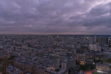 Eyfel Kulesi 'nin tepesinden Paris' in panoramik manzarası Alacakaranlık 'a kadar uzanır. Aydınlanmış sokaklar ve sıcak ışıkla yıkanmış klasik binalar. Derin mavi gökyüzü, şehrin zarafetini arttıran sakin bir atmosfer yaratır..