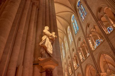 Paris 'teki Notre Dame Katedrali' nin içi Gotik sütunlarla, renkli camlarla ve sıcak ışıkla yıkanmış merkezi bir sunakla görkemli bir atmosferi ortaya çıkarır. Kompozisyon, oyma arasındaki dengeyi vurgular 