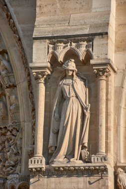 Paris 'teki Notre Dame cephesinin yakın çekimleri dini figürler, krallar ve azizlerin taç, cübbe ve sembolik objelerle resmedildiği yontulmuş taş heykeller ortaya çıkardı. Gotik kemerler ve tepe noktalarıyla çerçevelenen bu ortaçağ eserleri, ciddiyeti ifade ediyor.