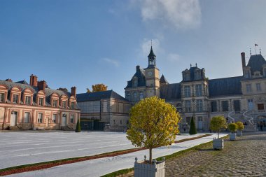 Paris, Fransa - 12 Ekim 2025, Fontainebleau Kalesi 'nin ana avlusu merkez kulesi, mansard çatıları ve taş ayrıntılarıyla simetrik bir cephe önündedir. Doğal ışık ve açık gökyüzü, mimarinin sıcak renklerini güçlendirir.