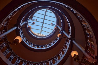 Fontainebleau Sarayı 'ndaki sarmal merdiven, süslü parmaklıklar ve doğal ışık sağlayan dairesel tavan penceresiyle yukarı doğru kıvrılır. Yukarı doğru perspektif ve geometrik simetri dinamik bir görsel kompozisyon oluşturur,