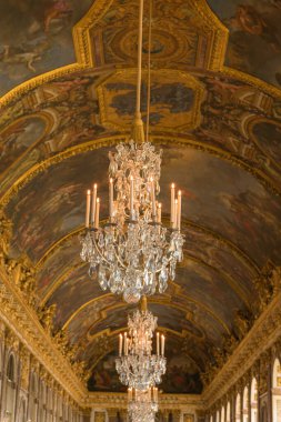 Versailles, Fransa-12 Ekim 2025, Versailles Sarayı 'ndaki Aynalar Salonu' nun tavanı, yaldızlı pervazlarla çerçevelenmiş ve yanında kristal lambalar asılı mitolojik ve alegorik sahneleri tasvir eden Barok freskleriyle süslenmiştir.. 