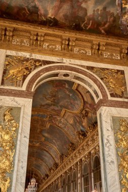 Versailles, Fransa-12 Ekim 2025, Versailles Sarayı 'ndaki Aynalar Salonu' nun tavanı, yaldızlı pervazlarla çerçevelenmiş ve yanında kristal lambalar asılı mitolojik ve alegorik sahneleri tasvir eden Barok freskleriyle süslenmiştir.. 