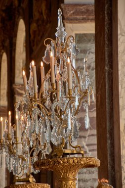 Versailles, Fransa-12 Ekim 2025, Versailles Sarayı 'nın içinde yaldızlı bir yapı, oyulmuş kristaller ve çevrenin süsleme detaylarını geliştiren sıcak bir ışık ile imparatorluk tarzı bir kolye bulunmaktadır.. 