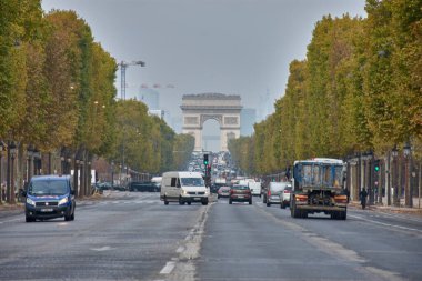 Paris, Fransa -15 Ekim 2025, Şanzelize Bulvarı 'ndan, Zafer Yayı' na sonbahar ağaçları ve Paris trafiği tarafından çerçevelenmiştir.. 
