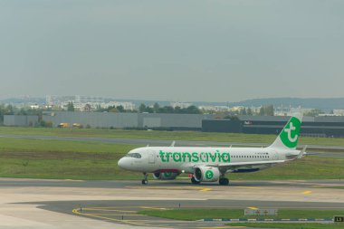 Porto, Portekiz-15 Ekim 2025, Porto 'daki Francisco Sa Carneiro Havaalanı' nın pistinde bir Transavia uçak taksisi, yeşil detaylar ve şirket logosuyla beyaz üniformasını vurguluyor.. 