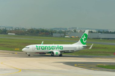 Porto, Portekiz-15 Ekim 2025, Porto 'daki Francisco Sa Carneiro Havaalanı' nın pistinde bir Transavia uçak taksisi, yeşil detaylar ve şirket logosuyla beyaz üniformasını vurguluyor.. 