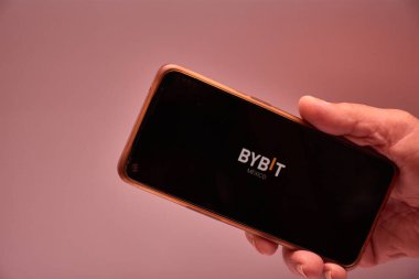 Vigo, İspanya, 30 Kasım 2025. Bir insan eli, ekranında şifreleme türevleri konusunda uzmanlaşmış Singapur merkezli bir döviz olan Bybit logosunu gösteren bir akıllı telefon tutar.. 