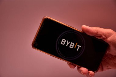 Vigo, İspanya, 30 Kasım 2025. Bir insan eli, ekranında şifreleme türevleri konusunda uzmanlaşmış Singapur merkezli bir döviz olan Bybit logosunu gösteren bir akıllı telefon tutar.. 