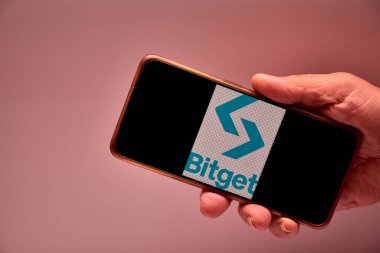 Vigo, İspanya, 30 Kasım 2025. Bir insan eli, ekranında Bitget logosu, önde gelen küresel kripto para birimi ve 100 milyondan fazla kullanıcının bulunduğu Web3 takas platformunu gösteren bir akıllı telefonu tutuyor.. 
