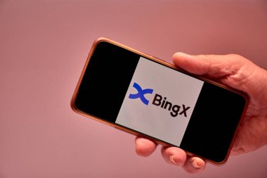 Vigo, İspanya, 30 Kasım 2025. Bir insan eli, ekranında 10 milyondan fazla kullanıcının bulunduğu uluslararası bir kripto döviz platformu olan BingX logosunu gösteren bir akıllı telefonu elinde tutuyor.. 
