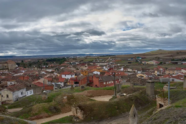 Palencia vilayetindeki Duenas 'ın panoramik manzarası, köyün kırmızı çatılı evleri ve Santa Maria de la Asuncion Kilisesi' nin dramatik, bulutlu gökyüzüne karşı ayakta duran kulesiyle birlikte yemyeşil bir tepeden gözler önüne seriliyor.. 