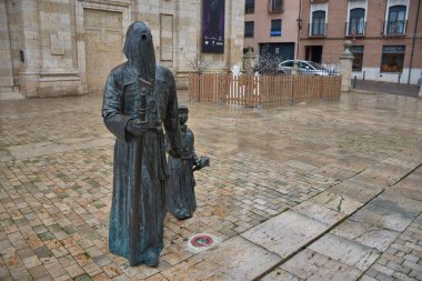 Medina de Rioseco 'daki bir meydanda yer alan gerçekçi bir bronz heykel, dini bir kardeşliğin çocuk üyelerinden birinin elini tutan sivri uçlu bir başlık giyen yetişkin bir tövbekar resmediyor. Parke taşı, ıslak çevre bulutlu bir günün ışığını yansıtır.