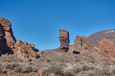 İspanya 'nın Tenerife Ulusal Parkı' ndaki Roque Cinchado 'nun heybetli dikey yapısı. Bazalt kayanın koyu renkleri, zirvenin beyazı ve Kanarya Adası gökyüzünün yoğun maviliği arasındaki çarpıcı tezat.