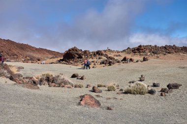 Teide, Tenerife, 13 Ocak 2026, bir grup ziyaretçi, Teide Dağı 'nın eteklerinde uzanan kireç kumu ve bazalt kayaları boyunca yürür..