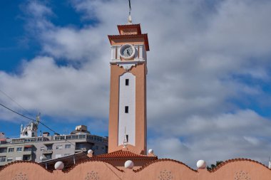 Bu yeni koloni tarzı saat kulesi canlı somon rengi ve dinamik mavi gökyüzüne karşı beyaz detaylarıyla göze çarpıyor. Perspektif, Santa Cruz de Tenerife 'nin bu ticari sembolünün dikeyliğini vurgular.