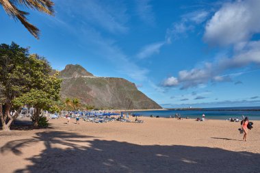 Santa Cruz de Tenerife, İspanya, 16 Ocak 2026, Banyo ve turistler volkanik dağların heybetli siluetinin altında, Santa Cruz de Tenerife, İspanya 'daki Las Teresitas' ın altın kumlarında dinlendirici bir günün tadını çıkarıyorlar..