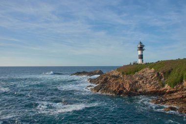 Ribadeo, Lugo, İspanya; 29 Mart 2025: Güneşli bir günde, eşsiz köprüsü ve güzel kıyı manzarasıyla Ribadeo 'daki büyüleyici ada Pancha. Açık mavi gökyüzü ve güneş ışığı adanın doğal cazibesini vurguluyor.