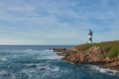 Ribadeo, Lugo, İspanya; 29 Mart 2025: Güneşli bir günde, eşsiz köprüsü ve güzel kıyı manzarasıyla Ribadeo 'daki büyüleyici ada Pancha. Açık mavi gökyüzü ve güneş ışığı adanın doğal cazibesini vurguluyor.