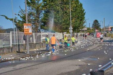 Nigran, Pontevedra, İspanya; 6 Nisan 2025: Yüksek görüşlü yelek giyen genç gönüllüler İspanya 'nın Nigran kentinde düzenlenen Vig Bay Half Marathon sırasında koşuculara suya batırılmış sünger dağıtıyorlar. Sahne, toplum desteği ve ekip çalışmasının bir anını partik olarak yakalıyor.