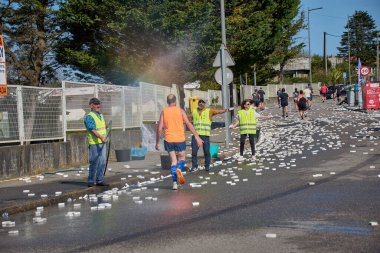 Nigran, Pontevedra, İspanya; 6 Nisan 2025: Yüksek görüşlü yelek giyen genç gönüllüler İspanya 'nın Nigran kentinde düzenlenen Vig Bay Half Marathon sırasında koşuculara suya batırılmış sünger dağıtıyorlar. Sahne, toplum desteği ve ekip çalışmasının bir anını partik olarak yakalıyor.