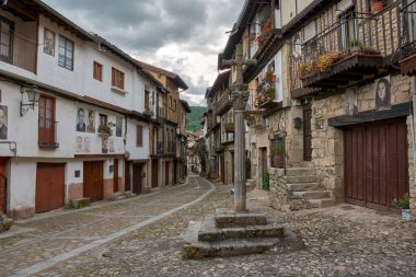 Salamanca 'nın Mogarraz köyünde ahşap balkonları ve taş duvarları olan geleneksel evlerle çevrili bir kaldırım taşı sokak. Ayırt edici bir unsur da, ön cepheleri süsleyen sakinlerin fotografik portreleridir.,