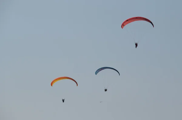 Three men flying on a red paraglider it the evening — Stock Photo, Image