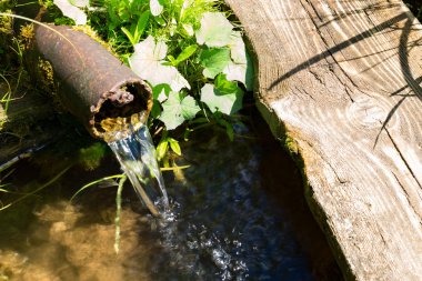 Bir borudan kaynak suyu akar.