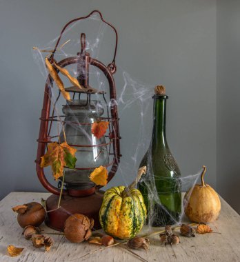 Eski bir gaz lambası, tozlu bir şişe, fındık ve kabak örümcek ağlarına sarılmış. Cadılar Bayramı.