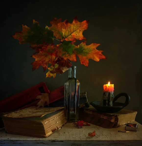 Still life with autumn leaves, burning candles and books. Vintage.