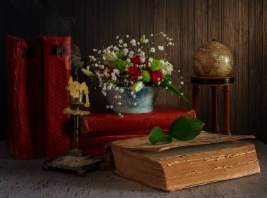 Bir demet çiçek, sönmüş bir mum ve kitaplar. Eski.