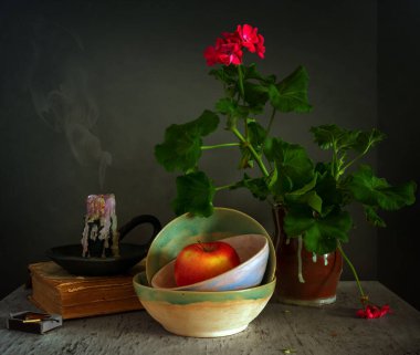 Çiçekli sardunyalar, sönmüş mumlar ve bir elmayla dolu sakin bir hayat. Eski model. Retro.