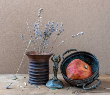 Olgun kırmızı nar, lavanta çiçekleri, antika bronz heykelcikler ve bakır çatal bıçaklarla dolu sakin bir hayat. Eski.