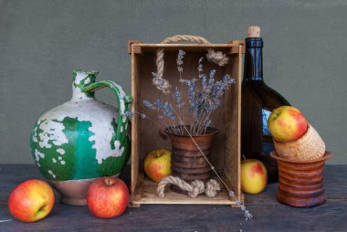 Eski bir seramik sürahi, soyulmuş boya, büyük koyu kahverengi bir şişe, seramik bir vazo, bir demet lavanta ve olgun elmalarla dolu bir hayat. Eski.