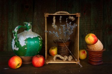 Eski bir seramik sürahi, soyulmuş boya, seramik bir vazo, kurumuş çiçekler ve olgun elmalarla dolu bir hayat. Eski.