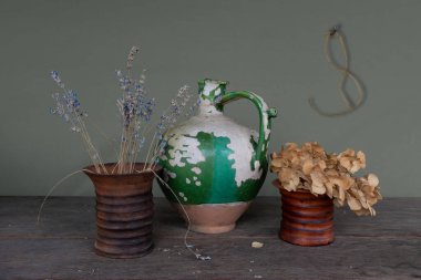 Çok eski bir seramik sürahi, kabuğu soyulmuş boya ve iki seramik vazo kurutulmuş çiçek. Eski.