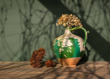 Çok eski seramik sürahi, kabuğu soyulmuş boya ve kurumuş çiçekler. Eski.