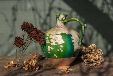 Çok eski seramik sürahi, kabuğu soyulmuş boya ve kurumuş çiçekler. Eski.